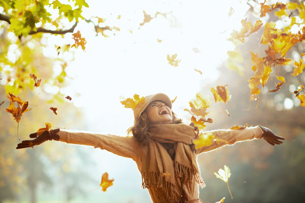 Frau wirft Blätter im Herbst in die Luft