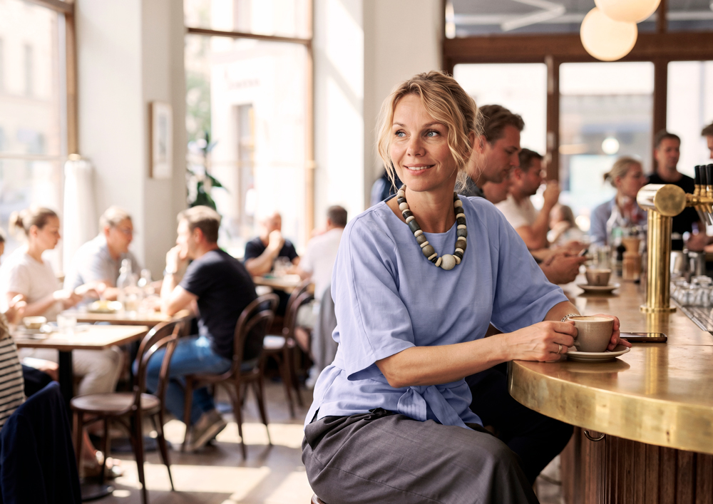 Frau mit Oticon Reveal Hörgeräten sitzt in einem Café